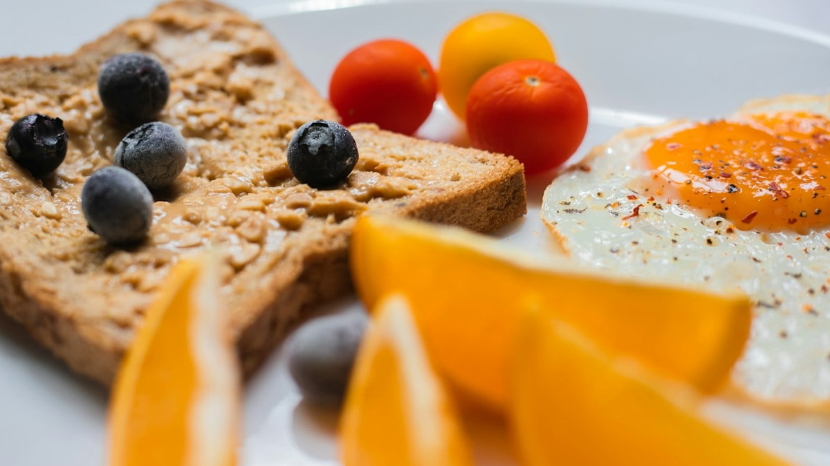 sliced bread with sliced orange and blue berries on white ceramic plate